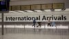 FILE - In this Jan. 26, 2021 file photo, arriving passengers walk past a sign in the arrivals area at Heathrow Airport in London, during England's third national lockdown since the coronavirus outbreak began. 