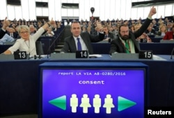 FILE - Members of the European Parliament vote in favor of the Paris climate change agreement during a voting session at the European Parliament in Strasbourg, Oct. 4, 2016.