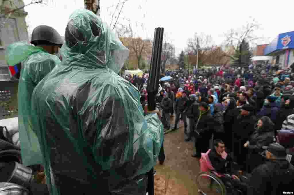 A pro-Russian armed man stands guard at a barricade in front of pro-Russian protesters near the police headquarters in Slovyansk, April 13, 2014. 