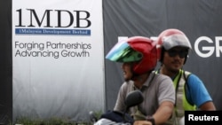 FILE - Motorcyclists pass a 1Malaysia Development Berhad (1MDB) billboard at the Tun Razak Exchange development in Kuala Lumpur, Malaysia, Feb. 3, 2016.