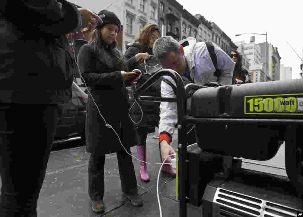 People in New York's Tribeca neighborhood, without power because of superstorm Sandy, wait for a chance to charge their mobile phones on an available generator setup on a sidewalk, Tuesday, Oct. 30, 2012.
