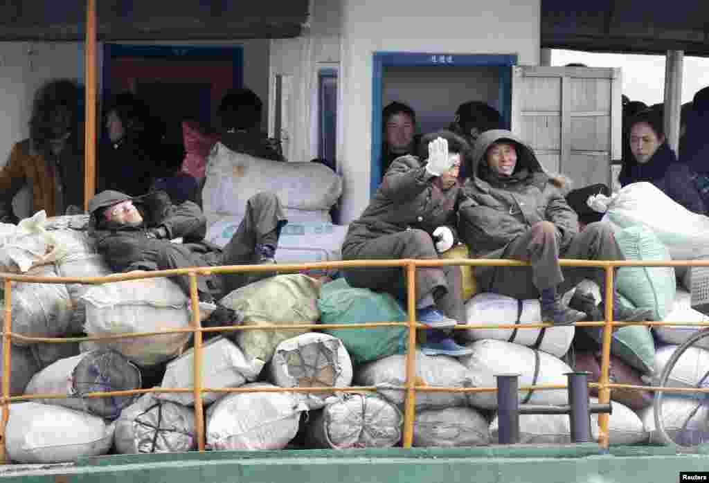 A North Korean man blocks his face with his hand from being photographed as he and other residents take a ferry in Yalu River, near the North Korean town of Sinuiju, opposite the Chinese border city of Dandong, April 11, 2013.