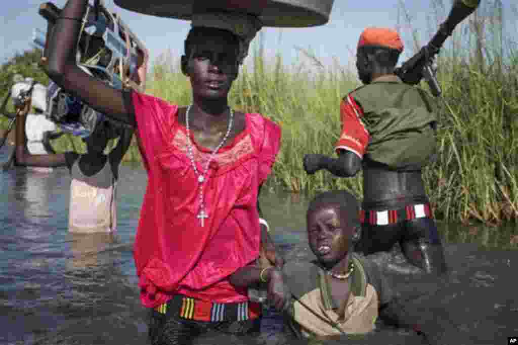 Une famille de l’ethnie Nuer à la recherche des mécadiments et de la nourriture, mais qui doit regagner leur village dans la zone contrôlée par des rebelles, prépare d’embarquer dans un canoë pour traverser une zone inondée où elle sera contrainte de marcher dans le marécage près de la Mission Onusienne au Sud Soudan (UNMISS) au village de Bentiu, au Sud Soudan.