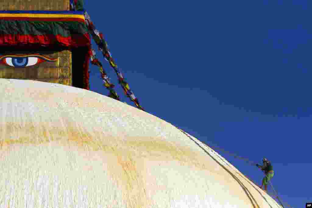 Seorang pria Nepal memanjat stupa &#39;Boudhanath&#39; di Katmandu, yang termasuk warisan dunia dan sedang menjalani renovasi. 