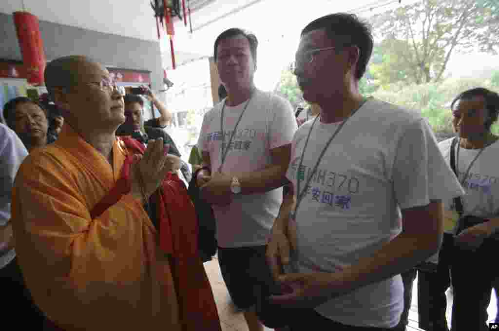 A Buddhist monk welcomes Chinese relatives of passengers on Flight MH370 as they arrive to pray at a Buddhist temple in Petaling Jaya, Malaysia, March 31, 2014.
