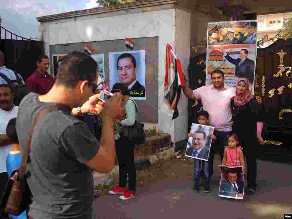 An Egyptian family poses for a portrait holding Mubarak's poster in front of Maadi Military hospital in 2015. (Photo: Hamada Elrasam / VOA)