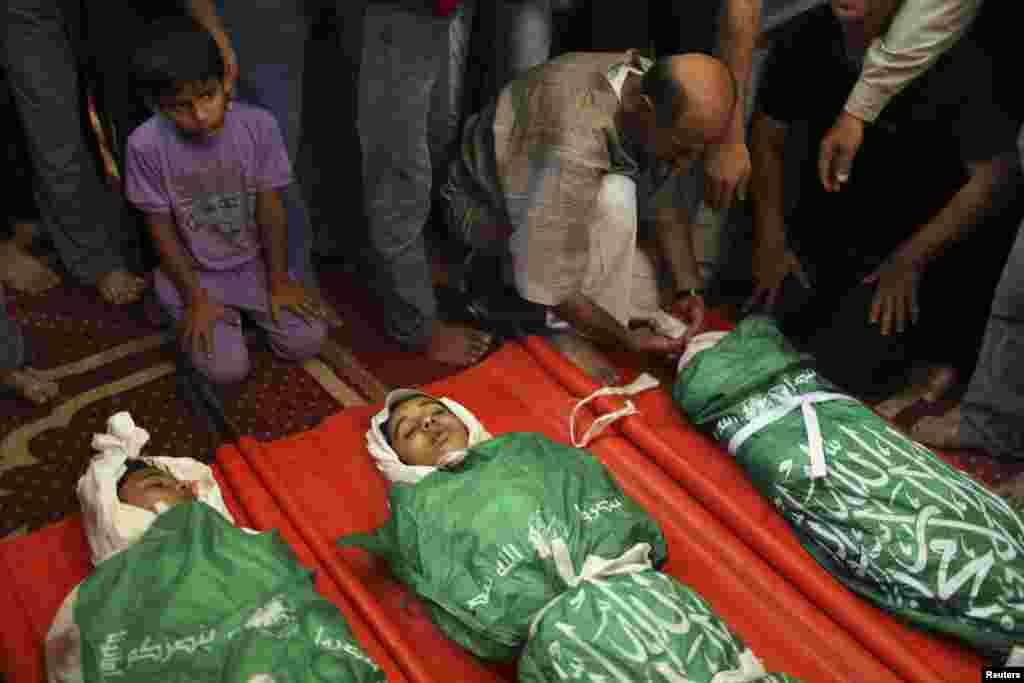 People gather around the bodies of three Palestinian teenage siblings from the Abu Musalam family, who medics said were shelled by an Israeli tank inside their house, during their funeral at a mosque in Beit Lahiya, in the northern Gaza Strip, July 18, 2014.