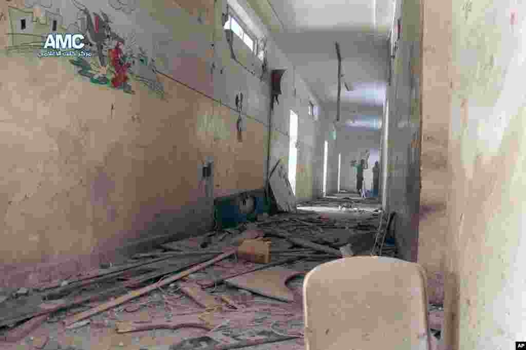 This photo provided by the anti-government activist group Aleppo Media Center shows two Syrian men standing inside a school that was hit by a Syrian government air strike in Aleppo, April. 30, 2014.