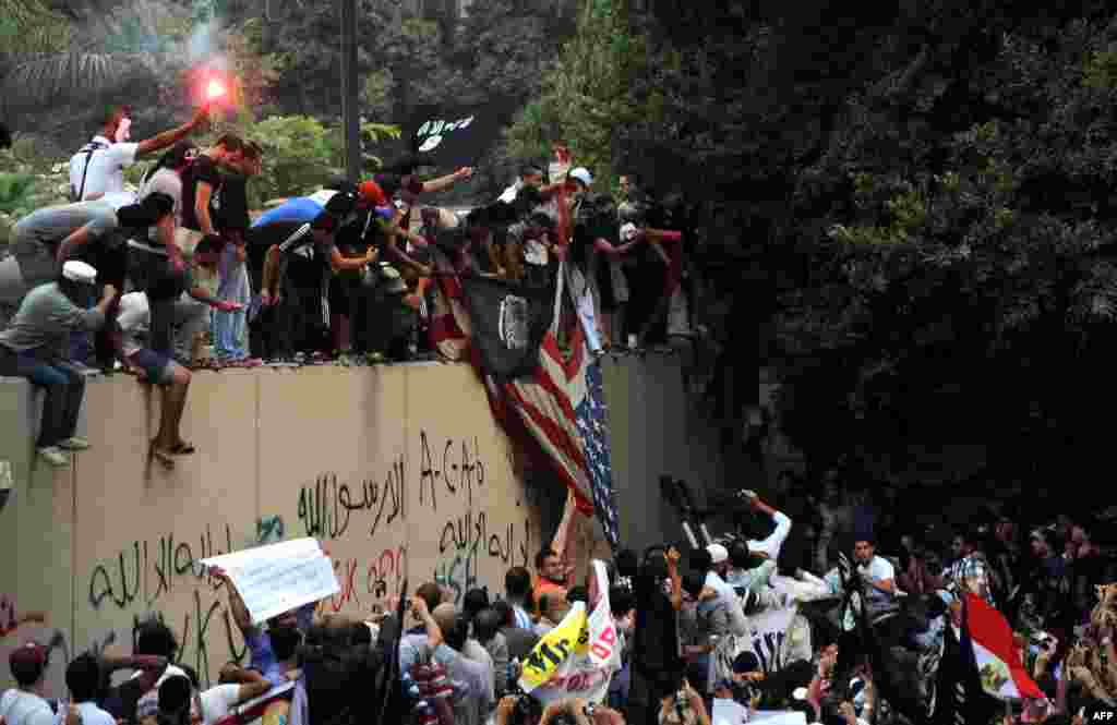 Para demonstran Mesir yang marah atas film yang menghina Islam, merobek bendera Amerika dan mengibarkan spanduk Islam berwarna hitam di gedung Kedutaan AS di Kairo (11/9).
