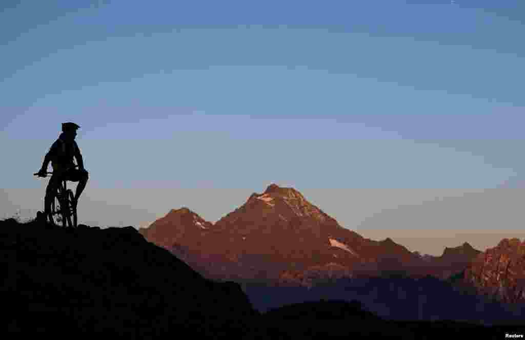A man waits on his mountain bike atop Eggerberg mountain during sunrise in the western Austrian village of Noesslach.