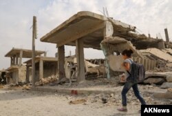 FILE - Syrian children walk past debris while heading to school on the second day of the new school year on Oct. 6, 2015 in the Syrian Kurdish town of Kobani.