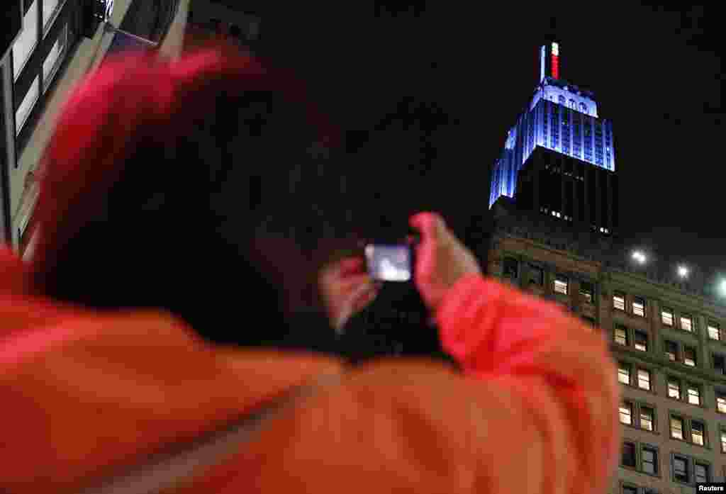 A woman takes a photo of the Empire State Building that is lit up in blue, the color of the Democrat Party, after Barack Obama was projected to win the U.S presidential election in New York, Nov. 6, 2012.