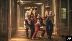 Joaquin Phoenix, foreground center, and Brendan Gleeson, background center, are seen in a scene from "Joker: Folie a Deux." (Niko Tavernise/Warner Bros. Pictures via AP)