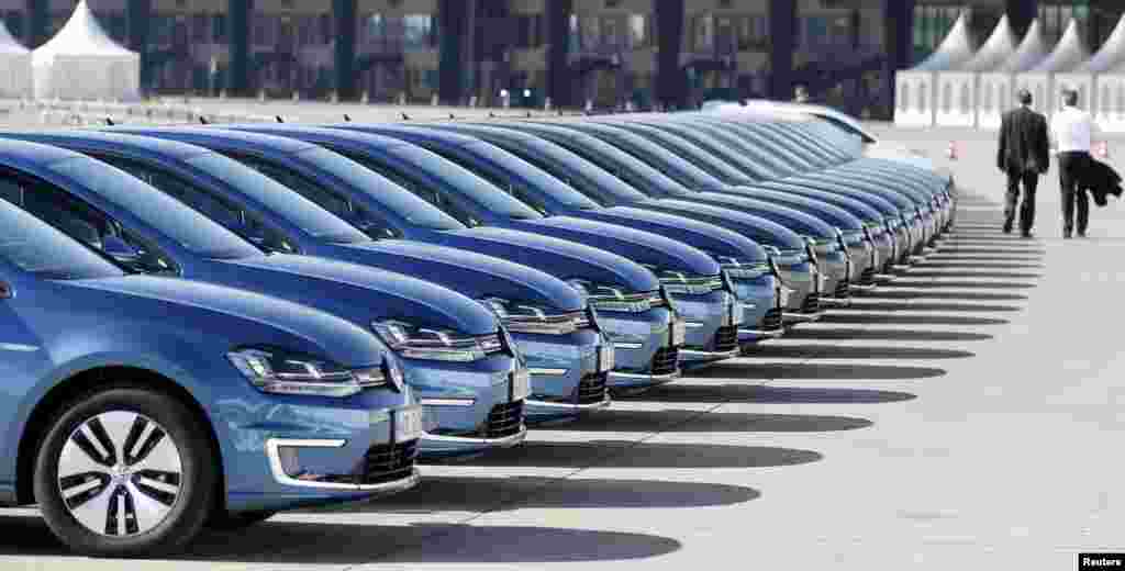 People walk past a row of Volkswagen e-Golf cars during the company's annual news conference in Berlin, Germany.