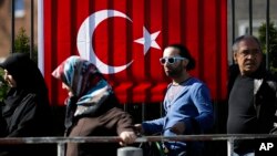 People wait outside the Turkish consulate in Berlin, March 27, 2017 to cast their votes on the first day of the referendum on the presidential system in Turkey. 