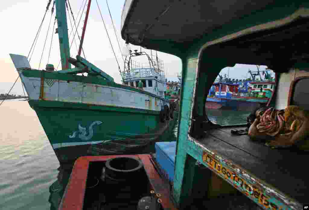 Seorang nelayan tidur di perahunya, sebelah kapal yang membawa para Muslim Rohingya dari Myanmar dan migran dari Bangladesh di pelabuhan Lhokseumawe, Aceh (14/5). (AP/Binsar Bakkara)