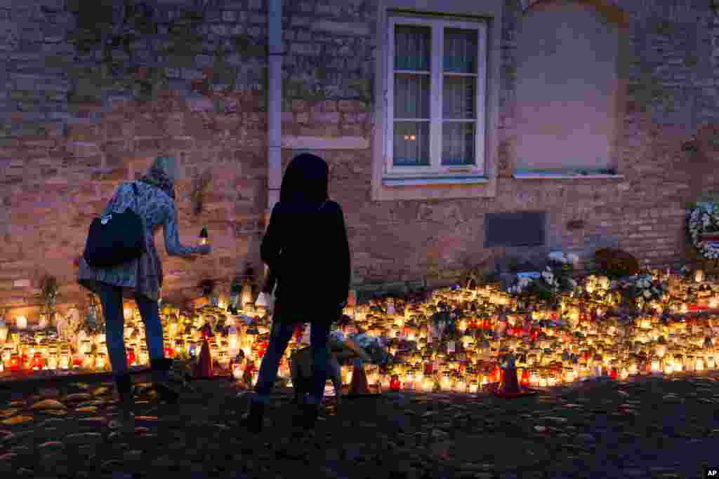 Warga menyalakan lilin di luar Kedutaan Besar Perancis di Vilnius, Lithuania (15/11), untuk para korban serangan maut di Paris. (AP/Mindaugas Kulbis)
