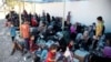 Des femmes et des enfants déplacés sont assis par terre dans un point de collecte pour personnes déplacées à l'ouest de Mossou, le 12 août 2017. (Photo AP / Balint Szlanko)
