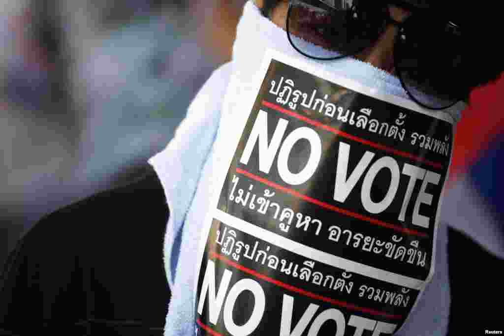An anti-government protester wears a mask made of "No Vote" stickers as he marches with others through Bangkok, Jan. 31, 2014.