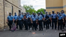 Para petugas kepolisian Minneapolis membentuk pagar betis menghadapi para pengunjuk rasa yang memprotes kematian George Floyd, di sebuah polsek, di Minneapolis, Minnesota, 27 Mei 2020. 