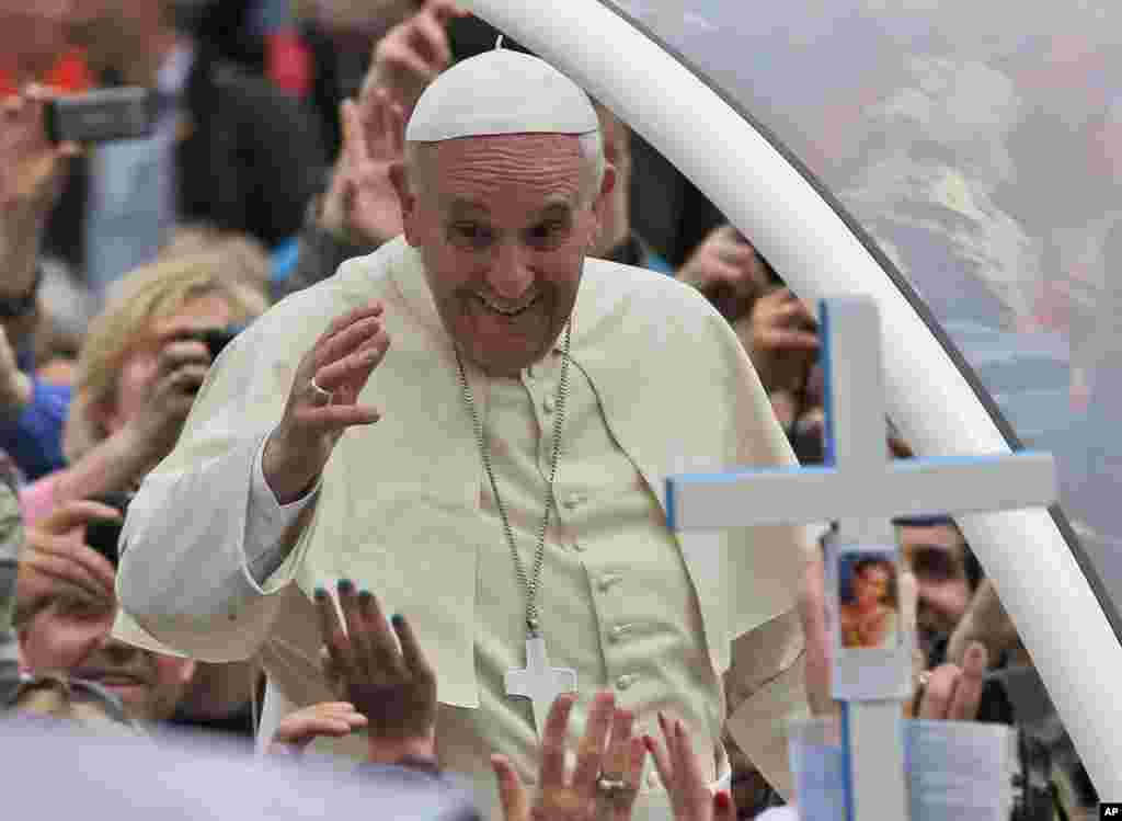 Pope Francis waves to the faithful as he is driven through the crowd after presiding over a solemn canonization ceremony in St. Peter's Square, the Vatican, April 27, 2014.