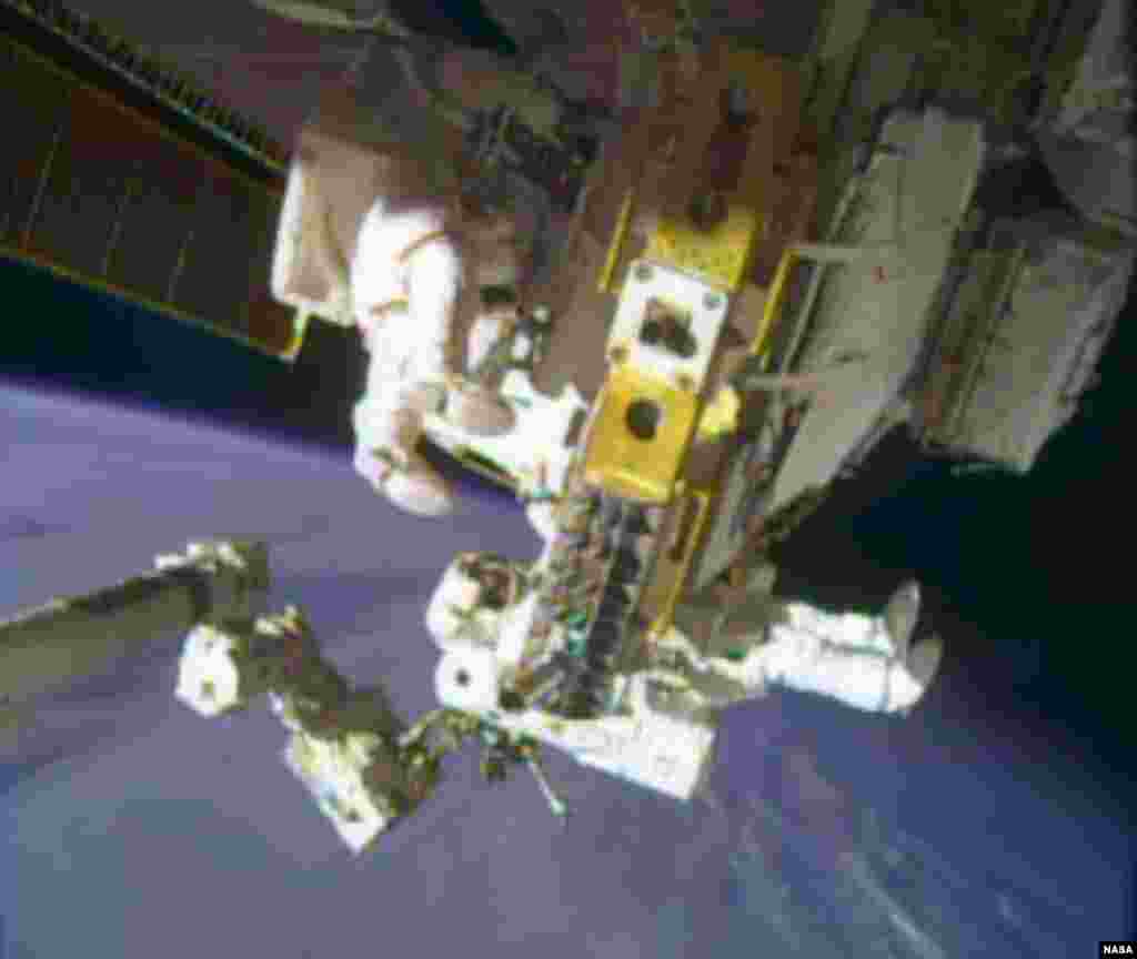 Astronauts Rick Mastracchio, top, and Michael Hopkins work to repair an external cooling line on the International Space Station, Dec. 24, 2013.