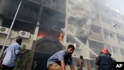 Petugas berusaha memadamkan kebakaran di gedung pemerintahan di Kairo yang diserang dan dibakar oleh para demonstran Mesir yang marah. (AP/Hassan Ammar)
