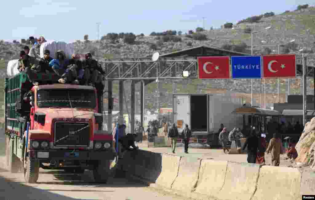 People sit on the top of a truck at the Syrian border crossing of Bab al-Hawa, at the Syrian-Turkish border, Feb. 6, 2014.