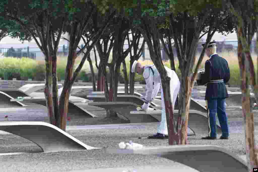 Members of the military honor guard place roses on top of the memorial benches at the 9/11 Pentagon Memorial, in Washington, Sept. 11, 2024.