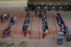 Asylum seeking migrant families from Central America await to be transported from a make shift U.S. Customs and Border Protection processing center under the Anzalduas International Bridge after crossing the Rio Grande river into the United States.