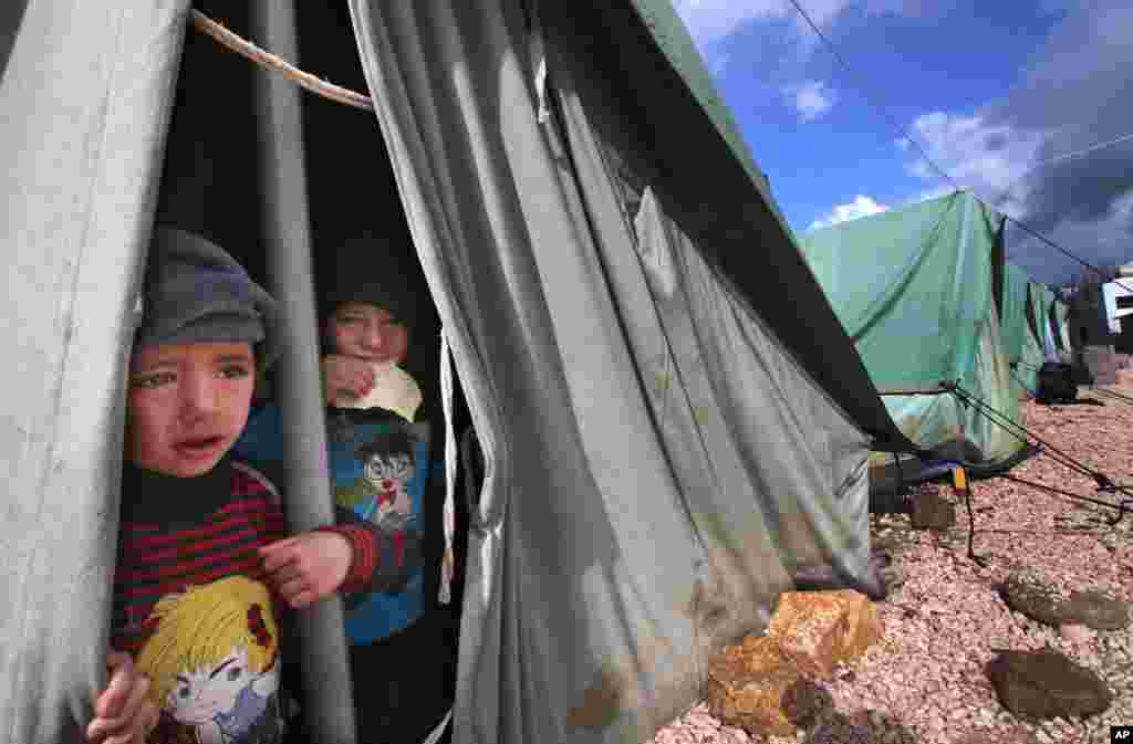 Syrian boys look outside their tent in Marj, Lebanon.
