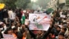 A protestor holds up a placard and sits with others in New Delhi, India, Dec. 19, 2019. 
