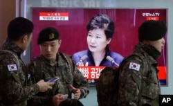 FILE - South Korean army soldiers pass by a TV screen showing the live broadcast of South Korean President Park Geun-hye's speech, at the Seoul Railway Station in Seoul, South Korea, Tuesday, Feb. 16, 2016.