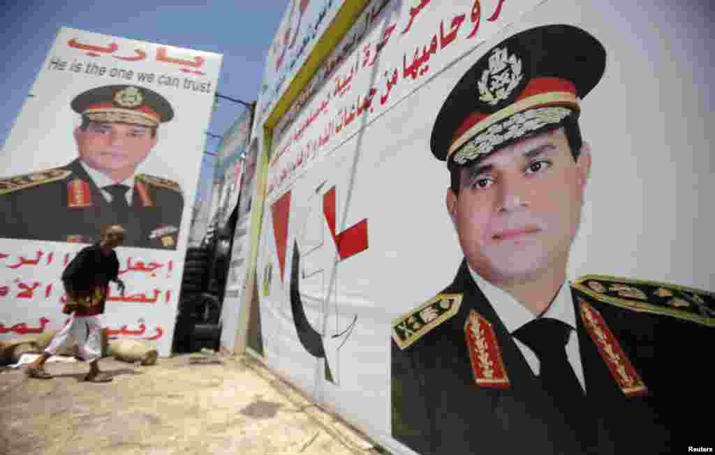 Salah Abdel Moneim, an anti-Morsi supporter of Egypt's army, walks in front of his shop, plastered with huge posters of Egypt's army chief General Abdel Fattah al-Sisi, Cairo, August 7, 2013.
