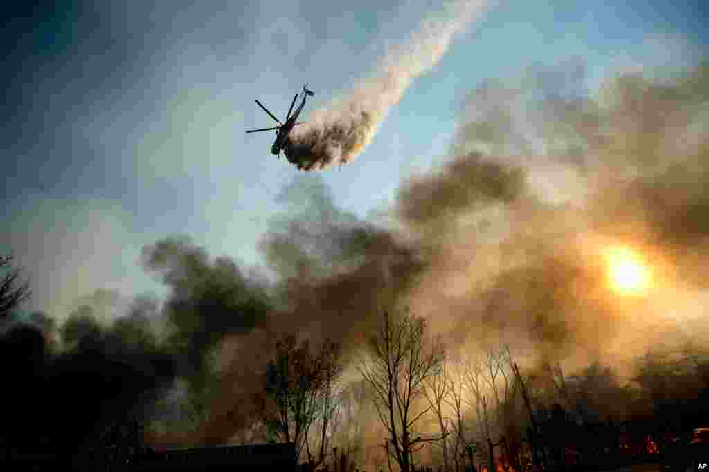 A helicopter drops water on a wildfire as it burns through Keenbrook, Calif., on Wednesday, Aug. 17, 2016.