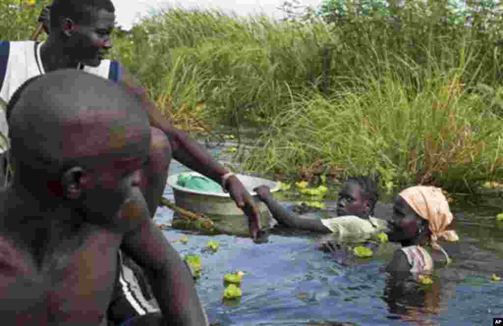 Une femme de l’ethnie Nuer retourne à son village après une marche longue d’une journée à travers une eau boueuse atteignant la poitrine où elle allait vendre des cas de braise aux déplacés au marché d’un camp situé près de la Mission Onusienne au Sud Soudan (UNMISS) au village de Bentiu, au Sud Soudan.