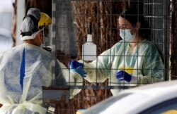 FILE - Medical staff prepare to take a COVID-19 tests at a drive through community based assessment centre in Christchurch, New Zealand, Aug. 13, 2020.
