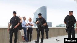 Armed Catalan Mossos d'Esquadra officers patrol along La Barceloneta beach in Barcelona, Spain, Aug. 19, 2017