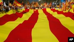 Des militants nationalistes protestent avec un drapeau géant catalan lors d'un rassemblement de masse contre la déclaration d'indépendance de la Catalogne, à Barcelone, en Espagne, le 29 octobre 2017.