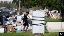 Lori Butler wipes her brow as she moves debris she is gutting from her home that was flooded, in the aftermath of Hurricane Ida in LaPlace, La., Sept. 7, 2021.