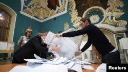 Members of a local election commission empty a ballot box before starting to count votes after polls closed, at a polling station inside Kazansky railway terminal in Moscow, Sept. 19, 2021.