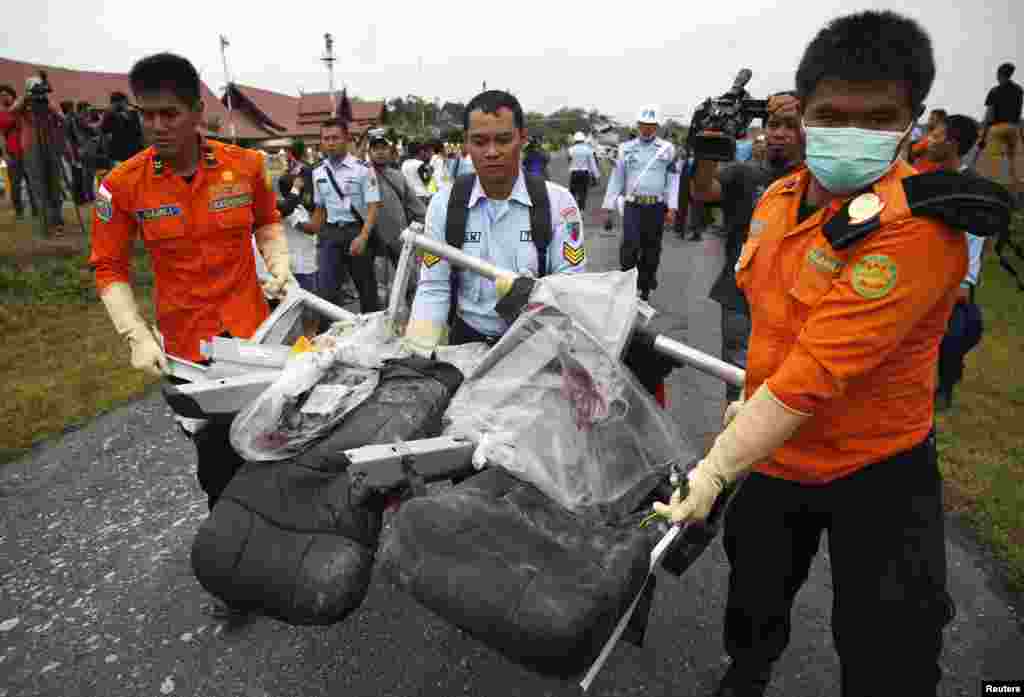 Bagian dari pesawat AirAsia bernomor penerbangan 8501, yang diambil dari Laut Jawa, diangkut dari helikopter Angkatan Laut AS di bandar udara di Pangkalan Bun, Kalimantan Tengah (5/1).(Reuters/Darren Whiteside)