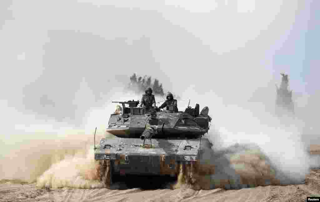 Israeli soldiers ride atop a tank outside the southern Gaza Strip, July 7, 2014.
