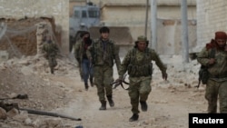 A rebel fighter runs with a weapon on the outskirts of the northern Syrian town of al-Bab, Syria, Jan. 26, 2017.