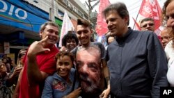 Workers' Party candidate for vice-president Fernando Haddad, 2nd from right, walks with a supporter who wears a shirt with a photo of former President Luiz Inacio Lula da Silva during a campaign rally in Rio de Janeiro, Brazil, Aug. 28, 2018.