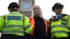 FILE- An activist from the group Just Stop Oil is arrested by police officers as they slow the traffic, marching on a road, in London, on Oct. 30, 2023. 
