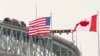 Bendera Amerika Serikat dan Kanada berkibar di dekat Jembatan Bluewater, yang melintasi Sungai St. Clair, perbatasan antara Sarnia, Ontario dan Port Huron, Michigan, 29 Januari 2025. (Geoff Robins/AFP)