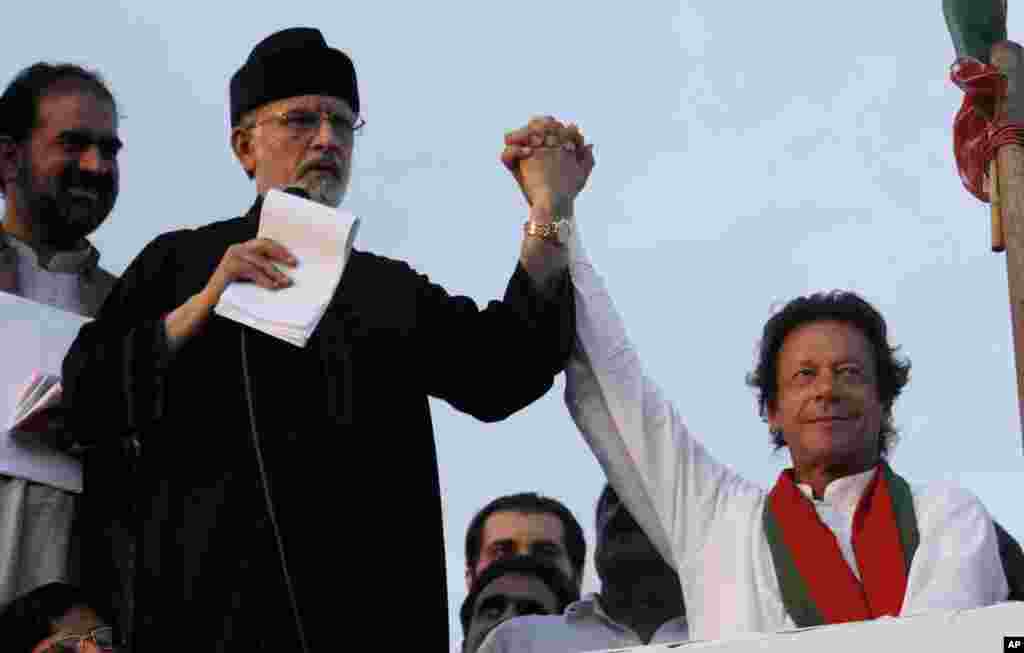 Pakistan's fiery cleric Tahir-ul-Qadri (second left) and cricketer-turned-politician Imran Khan (right), jointly raise their hands for their supporters during a protest near the prime minister's home in Islamabad, Sept. 2, 2014.