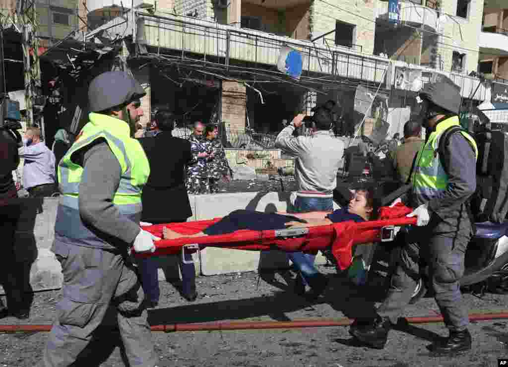 Lebanese civil defense workers carry an injured girl at the site of an explosion, near the Kuwaiti Embassy and Iran's cultural center, in the suburb of Beir Hassan, Beirut, Lebanon, Feb. 19, 2014.