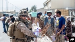 Marines with Special Purpose Marine Air-Ground Task Force-Crisis Response-Central Command (SPMAGTF-CR-CC) provide assistance during an evacuation at Hamid Karzai International Airport in Kabul, Afghanistan,Aug. 21, 2021.
